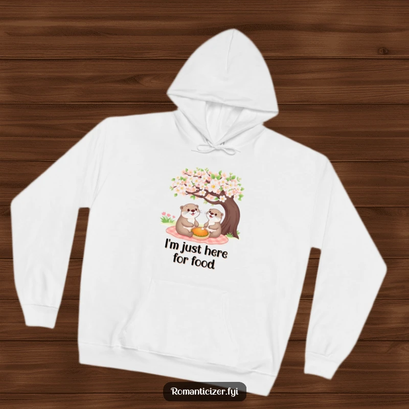 Funny cheerful otter hoodie design of a happy animal enjoying a picnic under a blooming tree, promoting warmth and cheerful vibes.